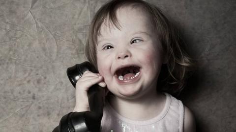 A young girl pretends to speak on an old telephone