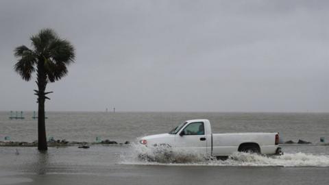 A driver navigates along a flooded road as the outer bands of Hurricane Sally come ashore on September 15, 2020 in Bayou La Batre, Alabama