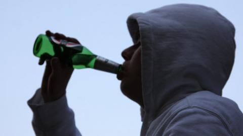 Teenage boy drinking alcohol outdoors