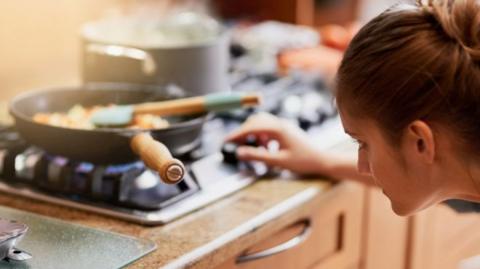 A woman cooks at a gas stove