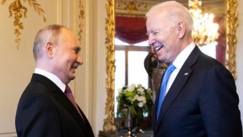 Putin and Biden laugh together in a luxuriously decorated room