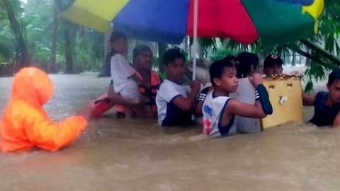 Philippine Coast Guard and residents use a broken refrigerator as a makeshift boat