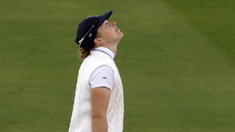 Heather Knight looks to the sky as it rains