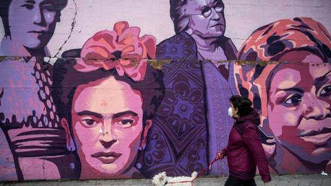 A woman with a dog walks past a feminist mural in Madrid