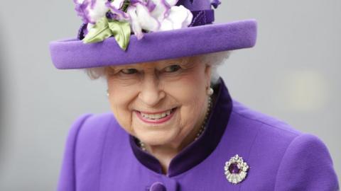 The Queen in purple dress and hat