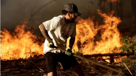 A local resident fights fire during a forest fire in Rafael, near Concepcion, Chile February 7, 2023