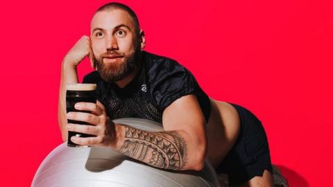 Morgan Rees lying on a yoga ball while holding a pint