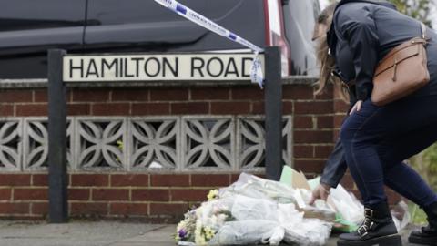 Woman lays flowers on Hamilton Road