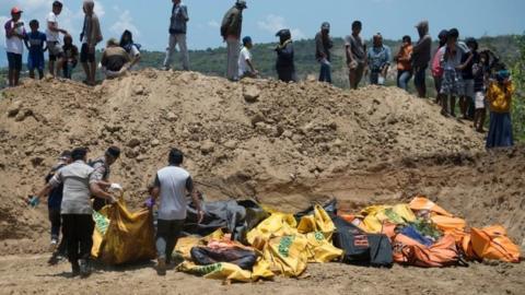 Officials carry body bags into a mass grave in Palu, Indonesia. Photo: 1 October 2018