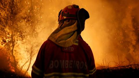 A firefighter is seen near flames from a forest fire in Cabanoes, near Lousa, Portugal on 16 October