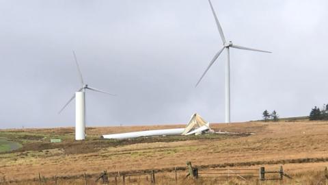 A broken wind turbine, snapped and blades crushed