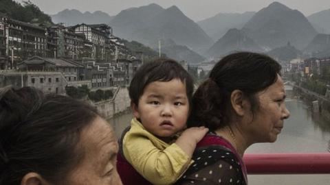 A Chinese woman carries a child across a bridge over the Chishui River