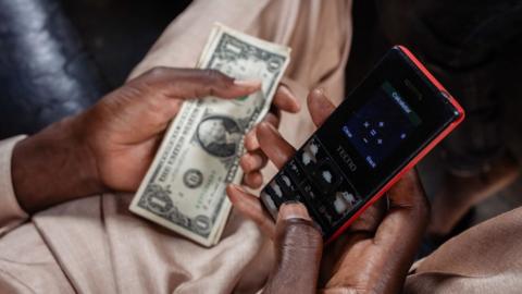 A street currency dealer uses a smartphone calculator app to calculate the rate for exchanging US dollar banknotes at a market in Lagos, Nigeria, on Monday, Sept. 25, 2023.
