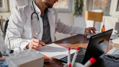 Doctor working at desk (stock image)