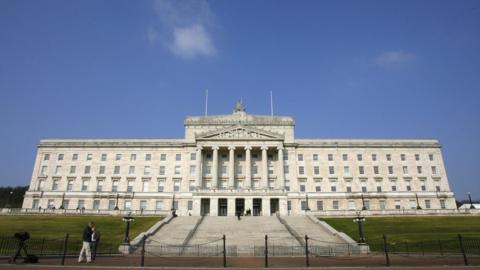 People walk past the Stormont Assembly building in Belfast