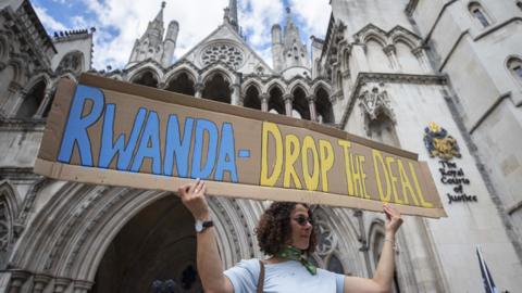 Woman holding a placard to protest the Rwanda asylum policy outside the Royal Courts of Justice