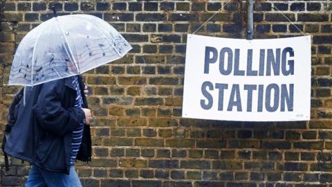 A man shelters from the rain, on his way to a polling station