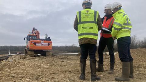 Three people stood on a building site