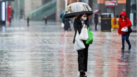 Shopper wearing a face mask and holding an umbrella