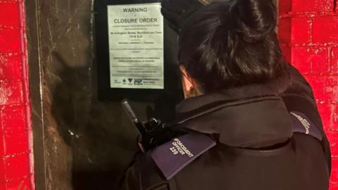 A female enforcement officer put a sign on a door