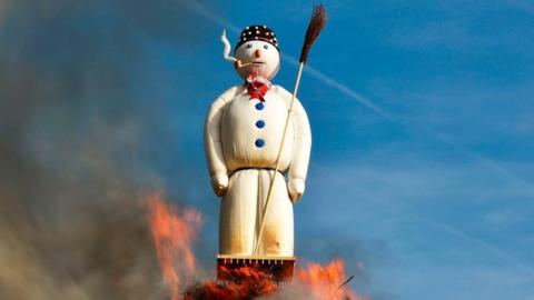 A giant snowman figure on top of a bonfire