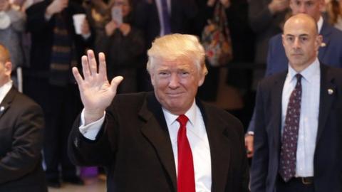 Donald Trump waves to the crowd as he leaves the New York Times building following a meetin