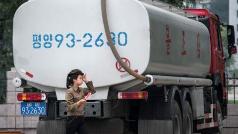 A petrol station worker walks past a fuel truck in Pyongyang