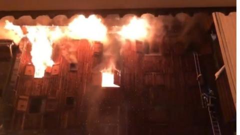 Still from a social media video shows fire coming from window of building
