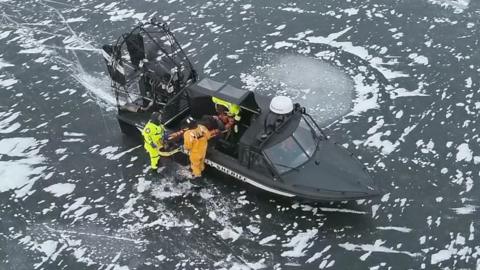 Stretcher being loaded into airboat on ice