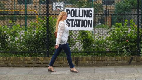 Woman walks past polling station sign