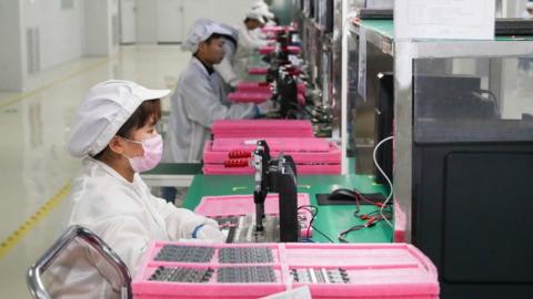 Employees work on the assembly line of printed circuit board for smartphone in Jiangsu Province of China.