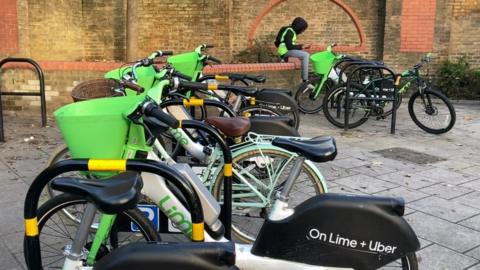 Rows of lime bikes parked in bike racks outside Wandsworth Town station