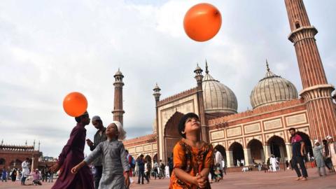 Indian children play with orange balloons