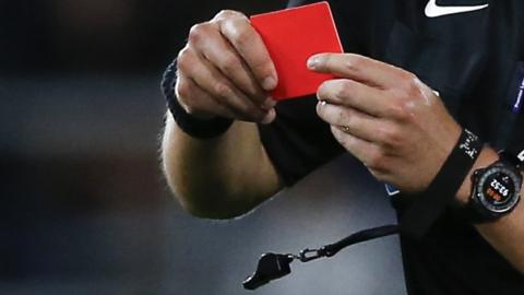 A football referee brandishes a red card