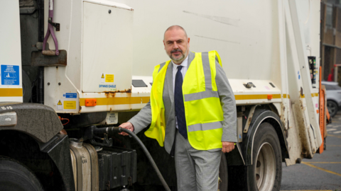 Man with a fuel pump next to a bin lorry