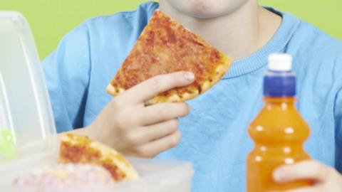 Boy holding pizza and a juice bottle