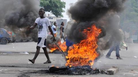 A man stands by a burning tyre during post-election violence in Ivory Coast in 2010