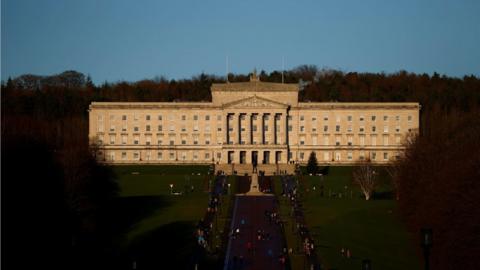 People walk through the grounds of the Stormont Parliament buildings in Belfast, Northern Ireland, on 30 December 2020.