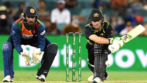 Josh Inglis attempts a sweep while Dinesh Chandimal looks on