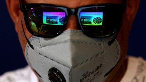 The screen of a laptop showing news about COVID-19 is reflected in the sunglasses of a man wearing a mask as a precaution against the coronavirus outbreak, in Bangalore, India, 04 March 2020