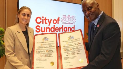 Stephanie Darby, nee Houghton, and Gary Bennett holding freedom of the city certificates