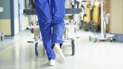 Hospital corridor with someone in scrubs pushing a trolley along