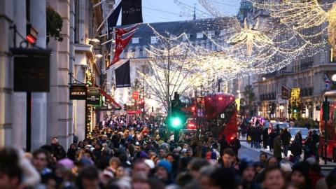 File image showing crowds of shoppers at dusk walking along Regent Street under Christmas lights