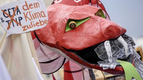 Protesters hold a giant snake with dollar notes in its mouth to demonstrate against the TTIP and CETA free trade agreements on Sept 17, 2016 in Berlin, Germany. The EU is currently negotiating with the US over TTIP and Canada over CETA