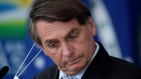 Jair Bolsonaro removes his mask at the Planalto Palace, in Brasilia, Brazil, 10 March 202