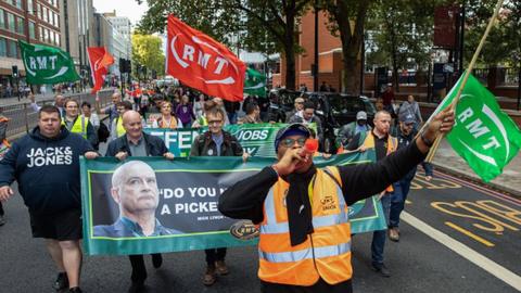 Mick Lynch, General Secretary of the National Union of Rail, Maritime and Transport Workers (RMT), marches with fellow RMT members in October