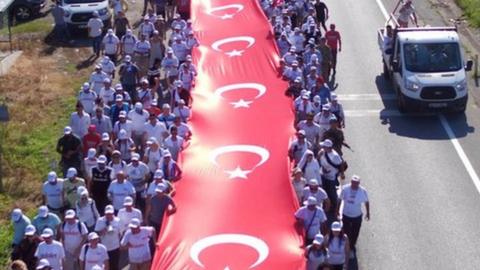 Thousands of supporters hold a long Turkish national flag on the march to Istanbul