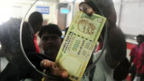 An Indian passenger uses a 500 rupee note to purchase rail tickets at Allahabad Railway station in Allahabad on November 9, 2016