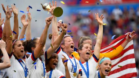 US women's national team players hold up the 2019 Women's World Cup trophy in celebration