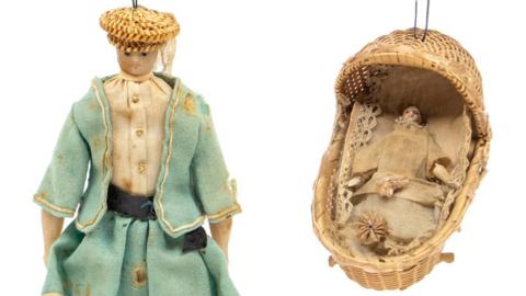 The doll inside a woven crib and wax doll missing a leg which had been owned by Queen Victoria